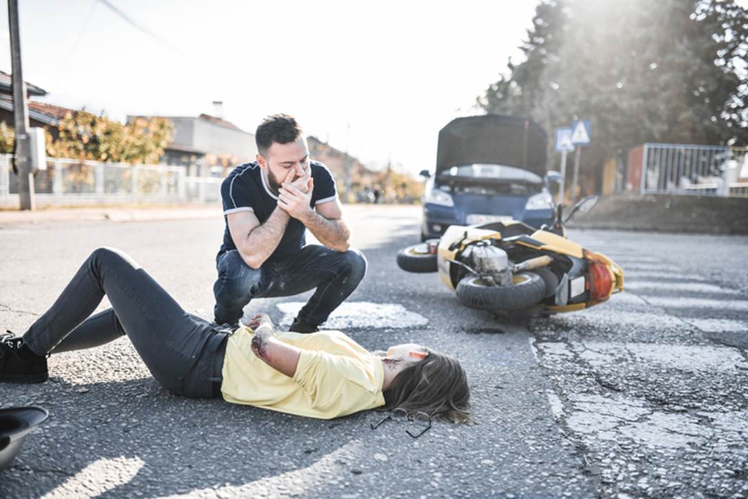 A person looking at a person lying on the ground next to a motorcycle

AI-generated content may be incorrect.